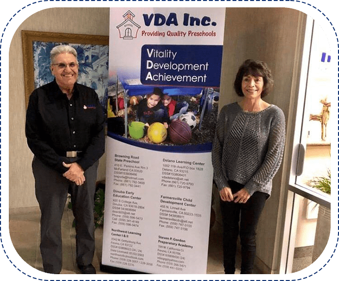 Two people standing next to a sign that says vda inc.