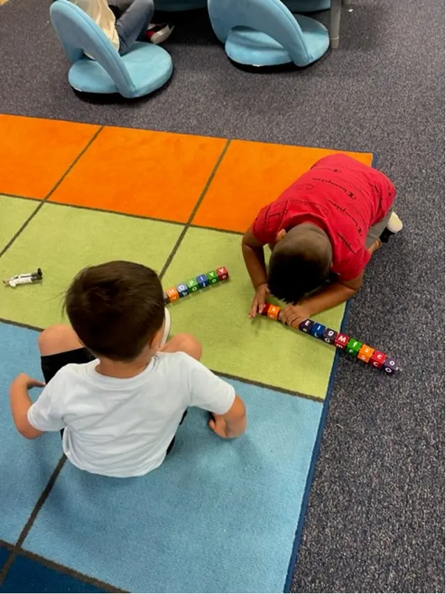 Two children are playing with a toy on the floor.