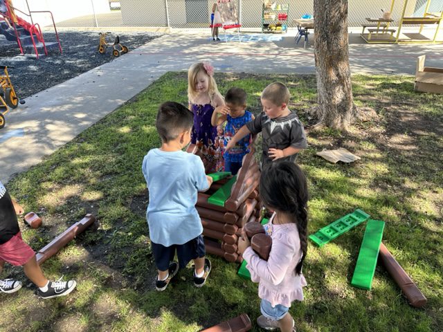 A group of children playing with blocks on the grass.